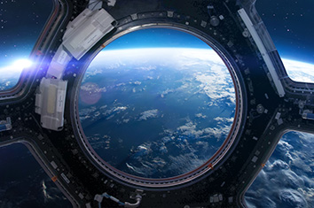 La Terre vue de l’espace à travers un hublot parmi d’autres hublots.