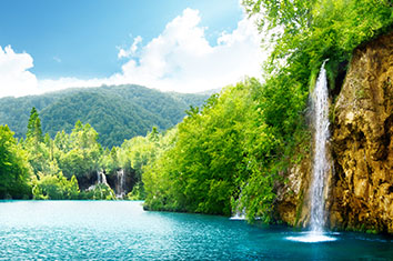 Une cascade se jette dans un lac entouré de forêt.