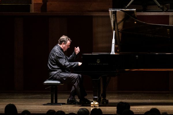 Ronan O''hara, on stage, sitting in front of a piano with a lifted hand